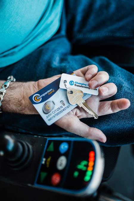 A hand holding a Companion Card and a Changing Places key