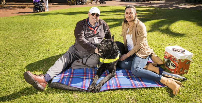 Two people sitting on a blanket with a guide dog, having entered the zoo using their Companion Card